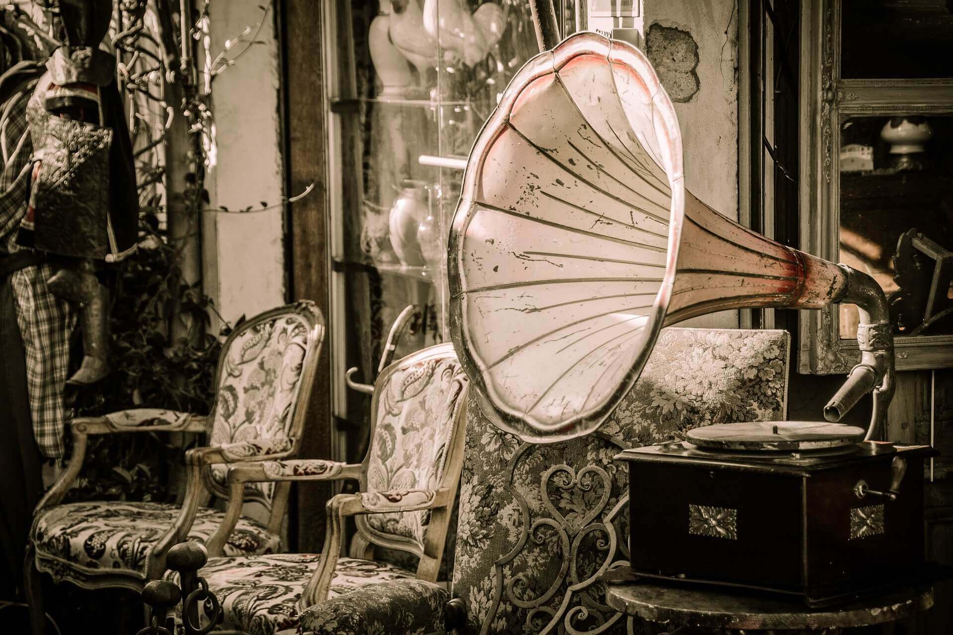 A large antique gramophone sitting in front of two chairs.