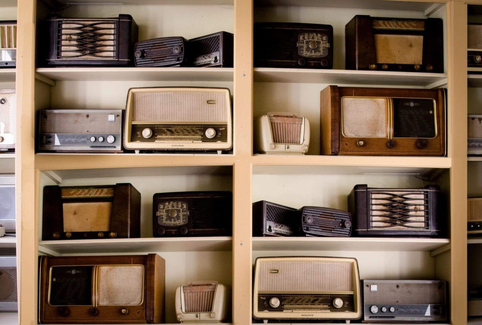 A shelf with many different types of old radio 's.