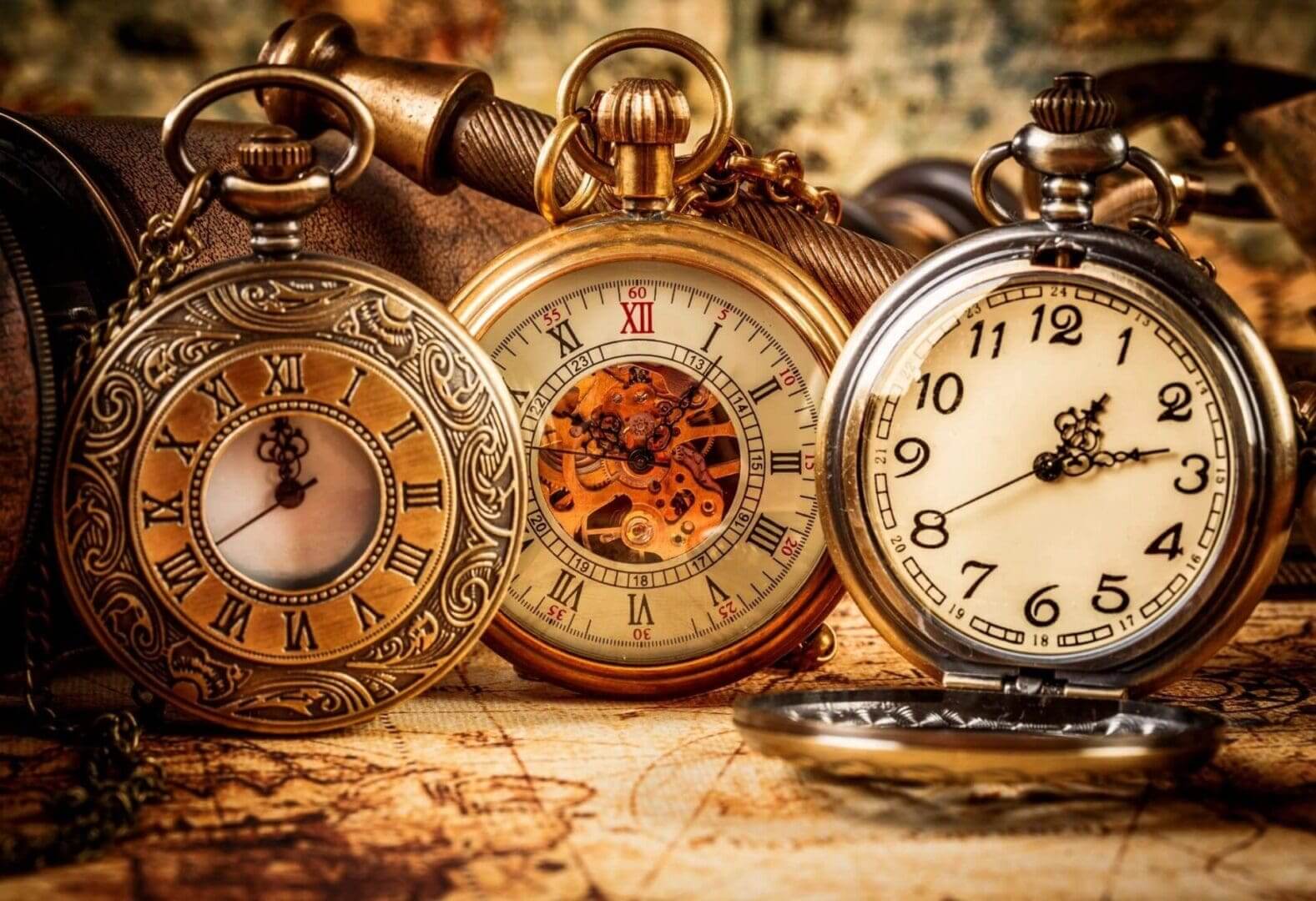 Three different clocks on a table with one of them showing the time.