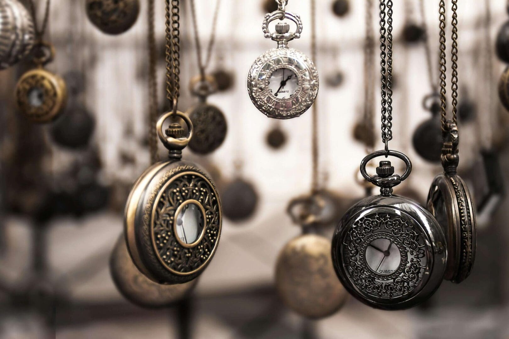 A bunch of different types of clocks hanging from chains.