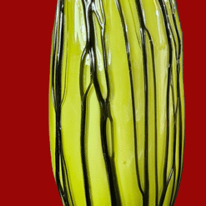 Tall greenish-yellow glass vase with black stripes on a red background.