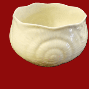 A white ceramic bowl with a textured spiral design on a red background.