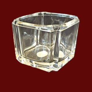 Clear glass container with a geometric shape on a black background.