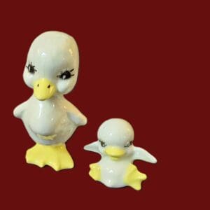 Two duck figurines, one large and one small, on a red background.
