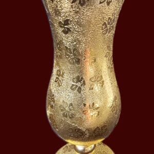 Ornate gold vase with intricate floral patterns on a dark background.