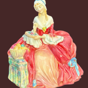 Porcelain figurine of a woman in an elegant pink dress sitting gracefully.