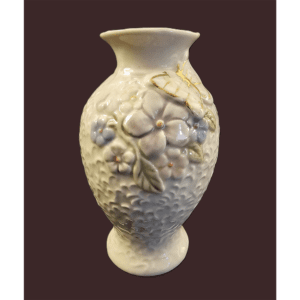 Ornate ceramic vase with floral relief design on a dark background.