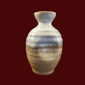 A ceramic vase with a gradient color pattern against a dark red background.