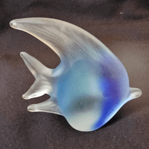 A delicate glass fish figurine with blue and white hues.