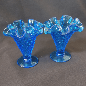 Two blue glass vases with ruffled edges and hobnail texture.