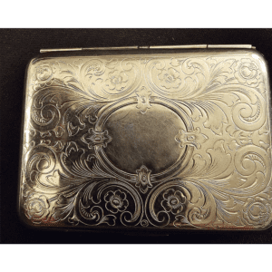 Intricately engraved silver cigarette case with floral and scroll motifs.