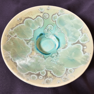 A ceramic plate with turquoise and beige glaze patterns.