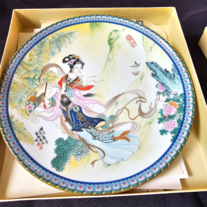 Ornate porcelain plate featuring a colorful, traditional Asian painting of a woman and nature.
