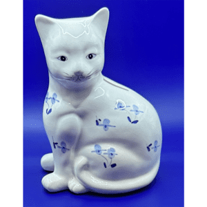 White ceramic cat figurine with blue floral patterns against a blue background.