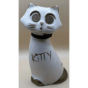A white cat figurine with 'KITTY' written on it and expressive eyes.