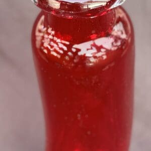 A glass jar filled with red chili sauce.