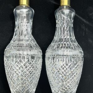 Pair of intricately cut crystal decanters with gold-colored stoppers.