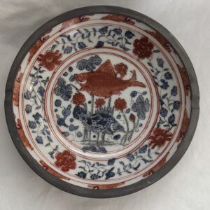 Decorative ceramic plate with floral and bird motifs in red, blue, and white.