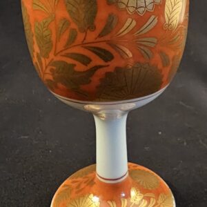 Decorative orange and white goblet with leaf patterns.