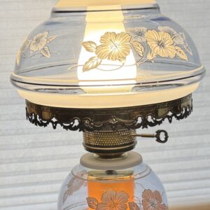 Antique glass oil lamp with floral decorations and ornate metalwork.